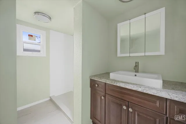 a bathroom with a granite countertop sink and a mirror