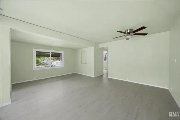 an empty room with a window and a ceiling fan