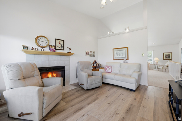 3766 Cardiff Circle Bountiful, UT 84010 - Photo 16 of 46 Living area featuring a fireplace with a tiled surround and wood mantel, vaulted ceilings, track lighting, and wood-finish flooring