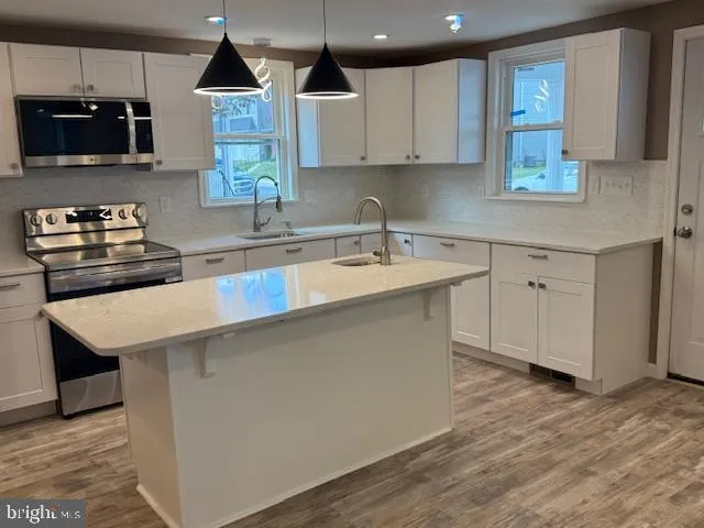 a kitchen with stainless steel appliances a stove a sink a microwave and cabinets