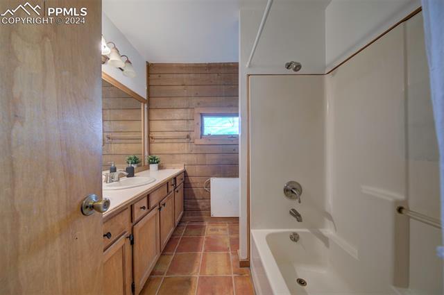 19350 Lemesany Road Calhan, CO 80808 - Photo 23 of 46 Bathroom with wood walls, vanity, and tile flooring, tub/shower combo