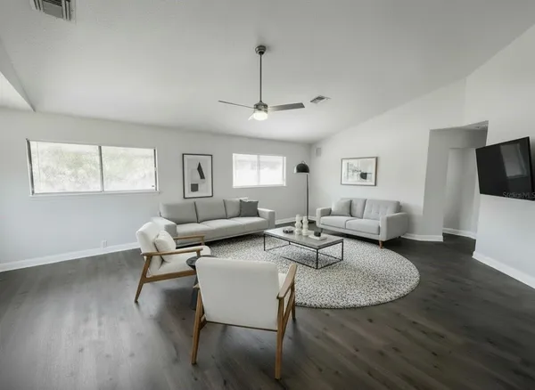 a living room with furniture a flat screen tv and a window