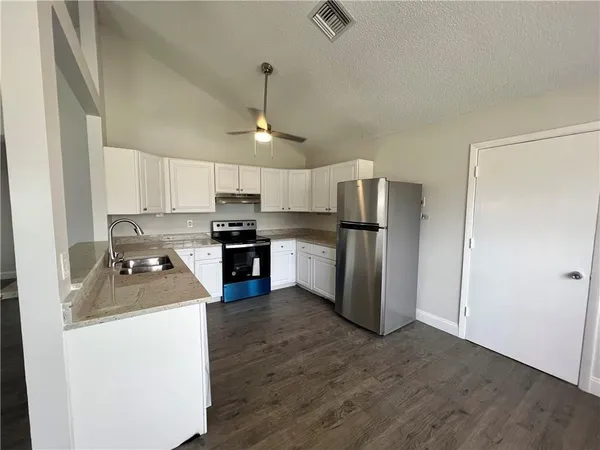 a kitchen with a refrigerator sink and cabinets