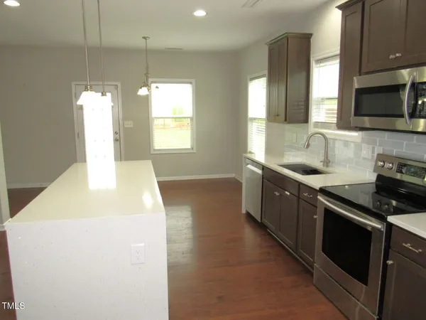 a kitchen with stainless steel appliances a stove a microwave a sink and cabinets
