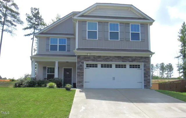 a front view of a house with a garden and garage