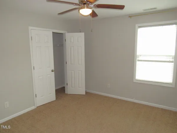 an empty room with a window and a fan