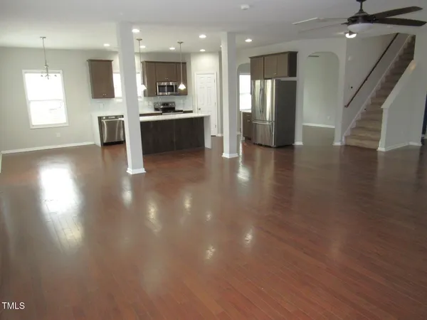 a kitchen with stainless steel appliances a sink a stove a refrigerator cabinets and a dining table