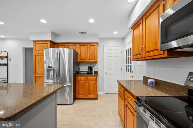 a kitchen with stainless steel appliances kitchen island granite countertop a refrigerator and a stove