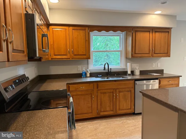 a open kitchen with stainless steel appliances kitchen island granite countertop a refrigerator and a sink
