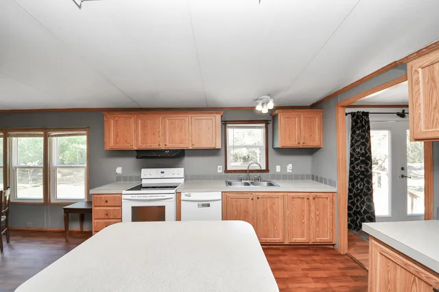 a kitchen with a refrigerator a stove top oven a sink and dishwasher with wooden floor