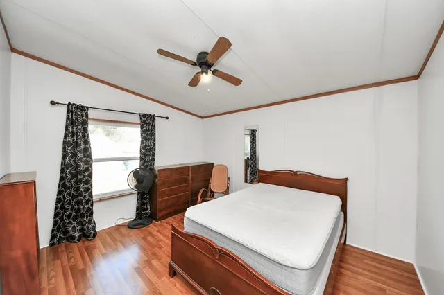 a bedroom with a bed and a dresser with wooden floor