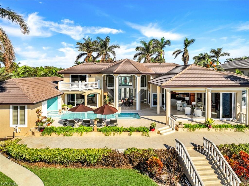 856 Inlet Drive Marco Island, FL 34145 - Photo 32 of 35 a front view of a house with swimming pool lawn chairs and potted plants