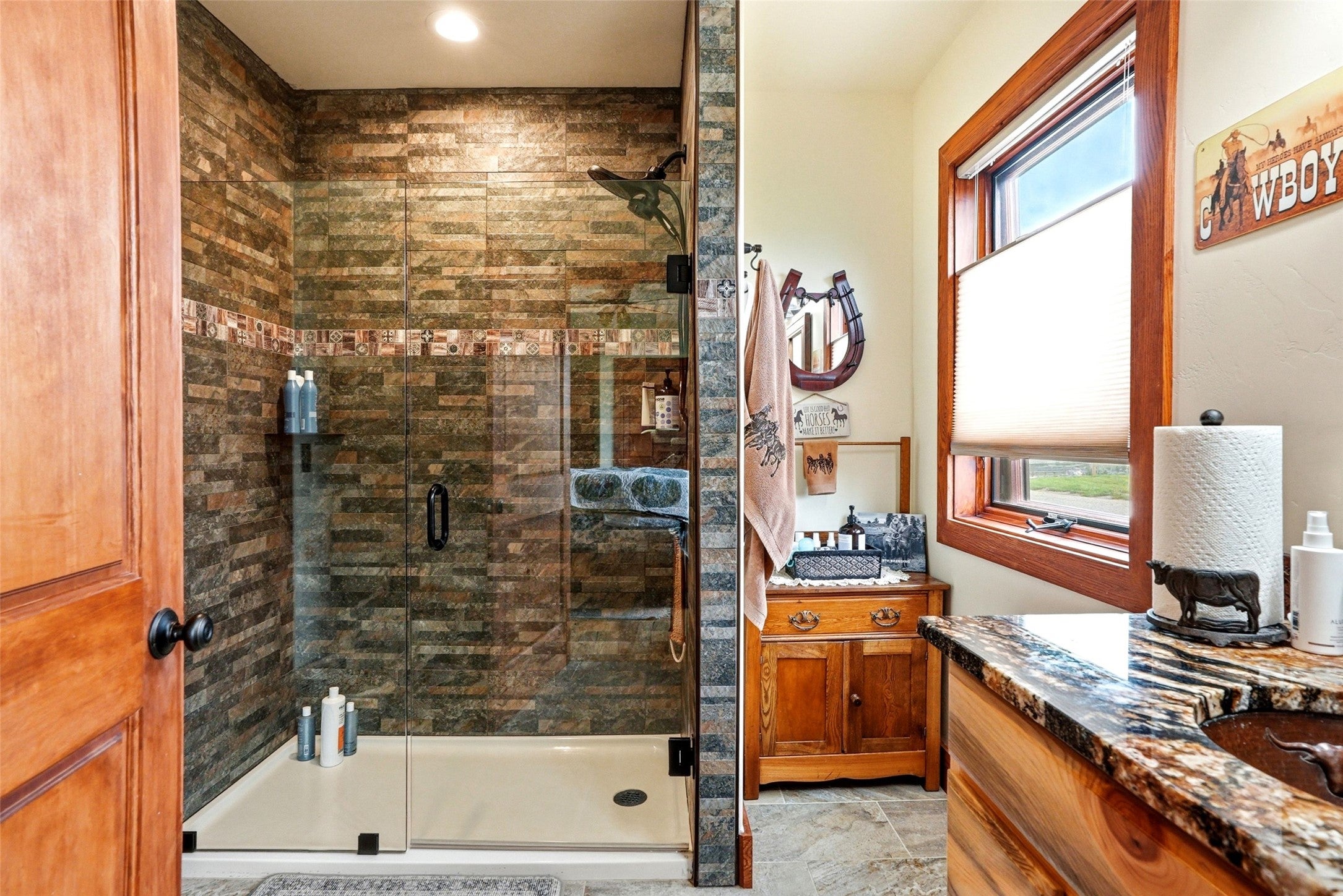 679 Hidden Valley Road North Florence, MT 59833 - Photo 31 of 85 Walk-in shower featuring stacked stone-look tile, glass enclosure with black hardware, and a durable shower pan