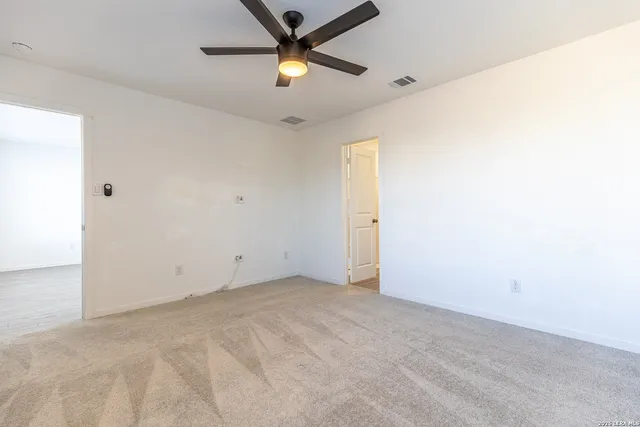 an empty room with a ceiling fan and carpet