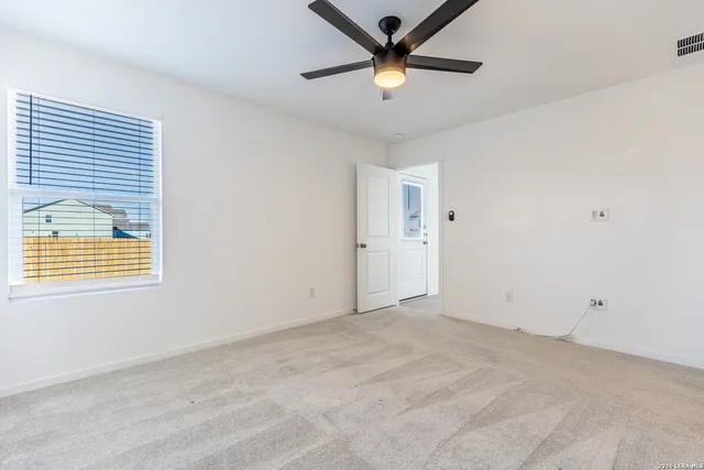 an empty room with a window and a fan