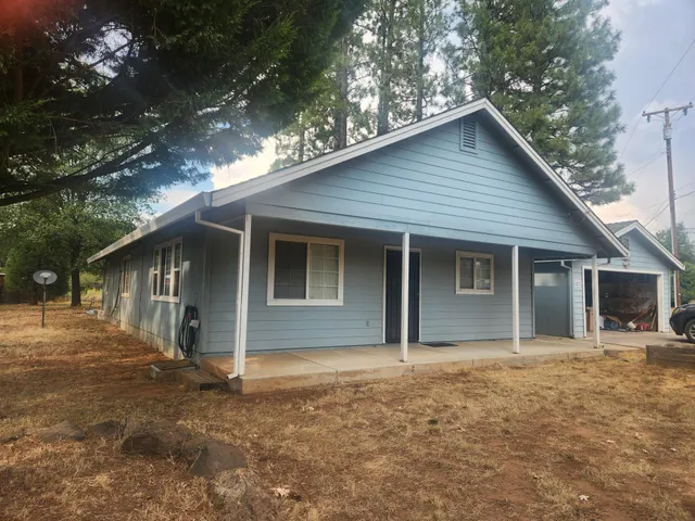 a front view of house with yard and trees in the background
