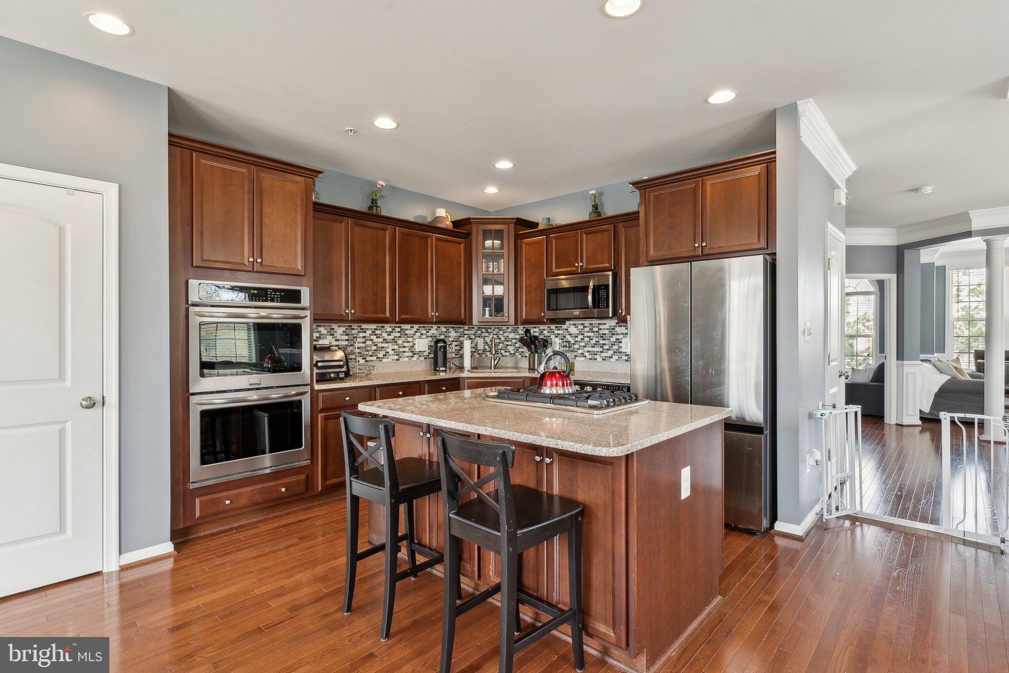 305 Hersden Lane Arnold, MD 21012 - Photo 4 of 23 a kitchen with granite countertop a refrigerator a stove a sink dishwasher a dining table and chairs with wooden floor