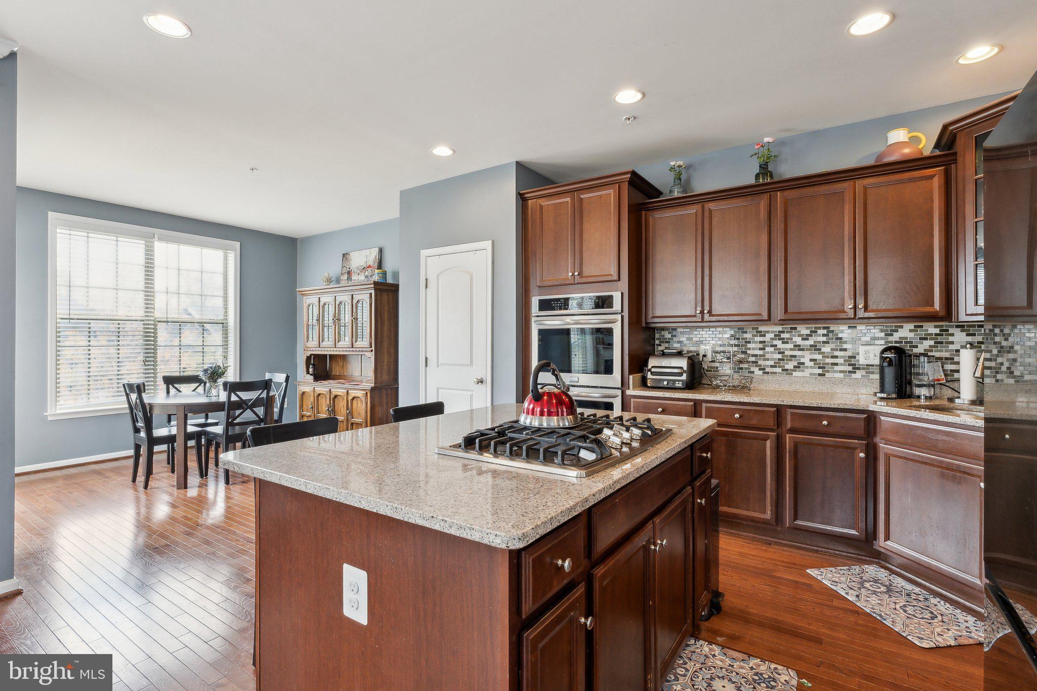 305 Hersden Lane Arnold, MD 21012 - Photo 5 of 23 a kitchen with stainless steel appliances granite countertop a stove top oven a sink dishwasher a dining table and chairs with wooden floor