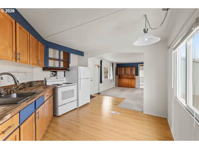 a kitchen with stainless steel appliances granite countertop a refrigerator a sink dishwasher stove and white cabinets with wooden floor