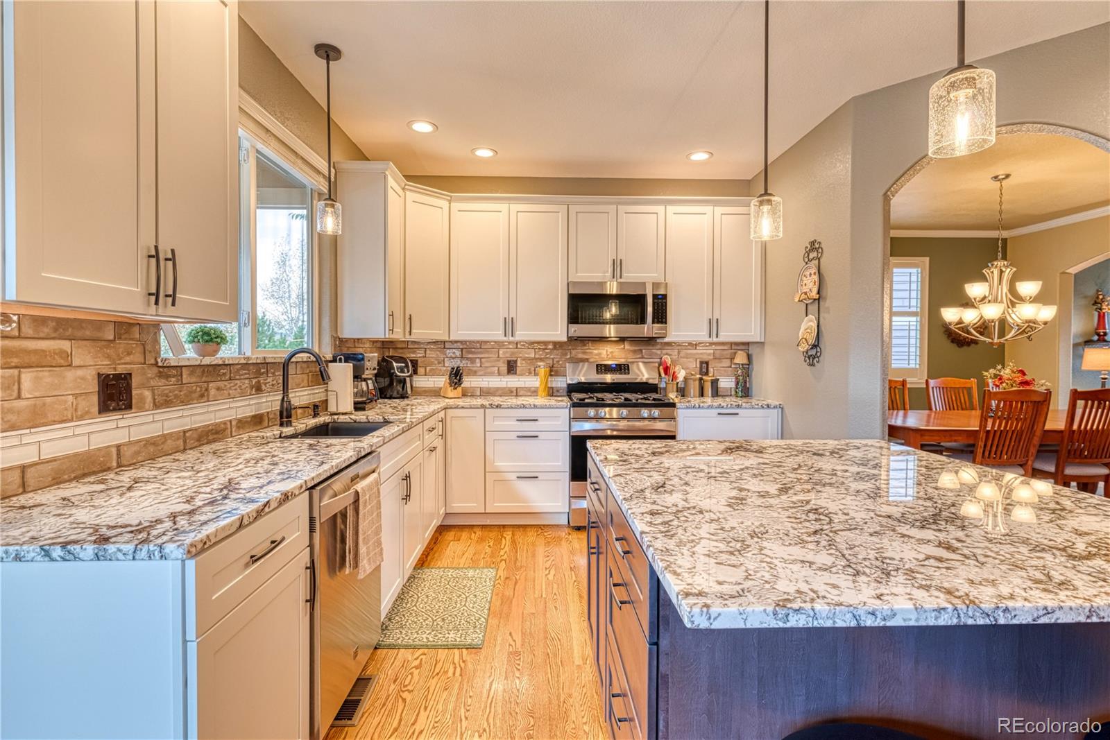 6378 Umber Circle Arvada, CO 80403 - Photo 22 of 50 a large kitchen with kitchen island granite countertop a large island in the center