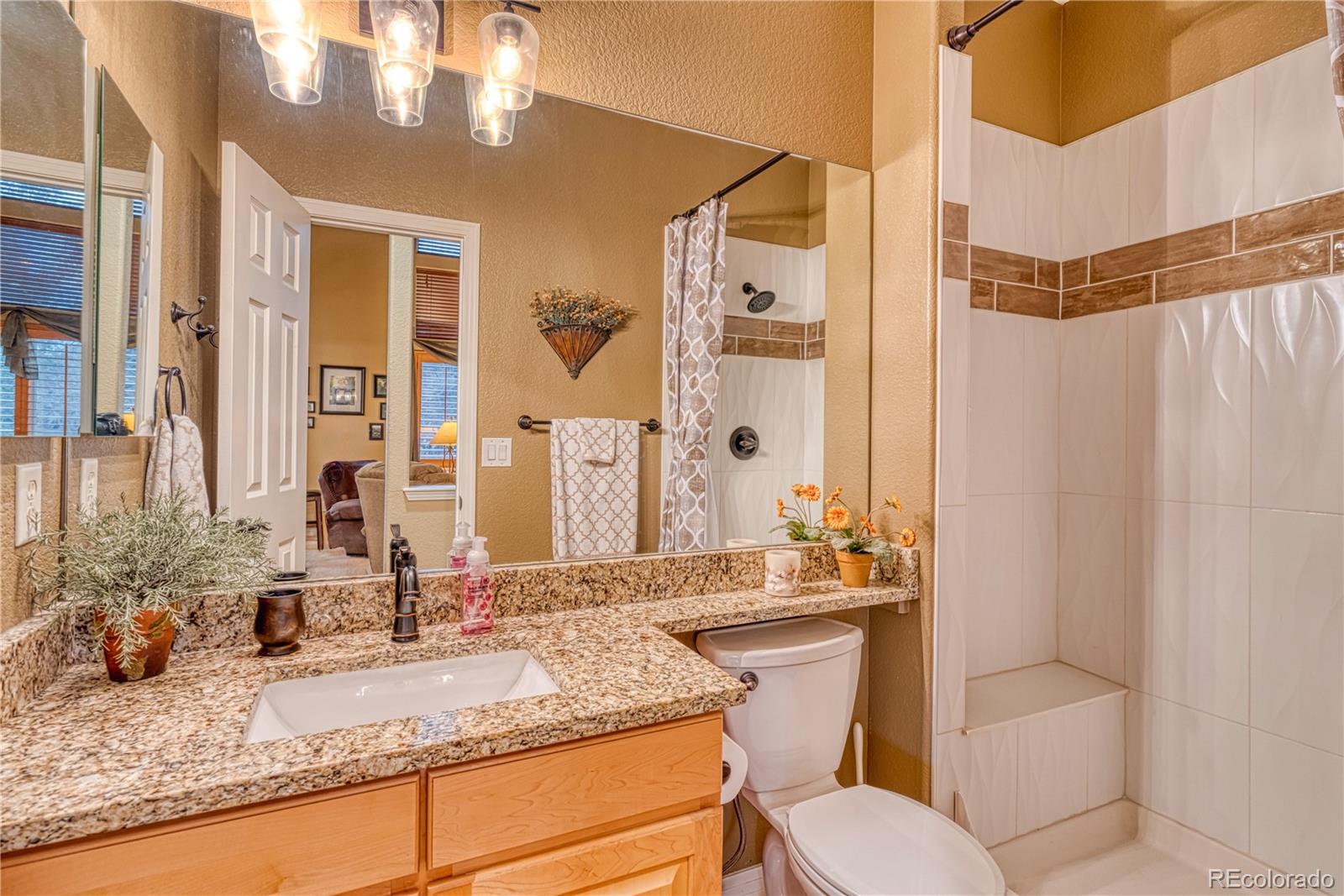 6378 Umber Circle Arvada, CO 80403 - Photo 32 of 50 a bathroom with a granite countertop sink toilet and shower