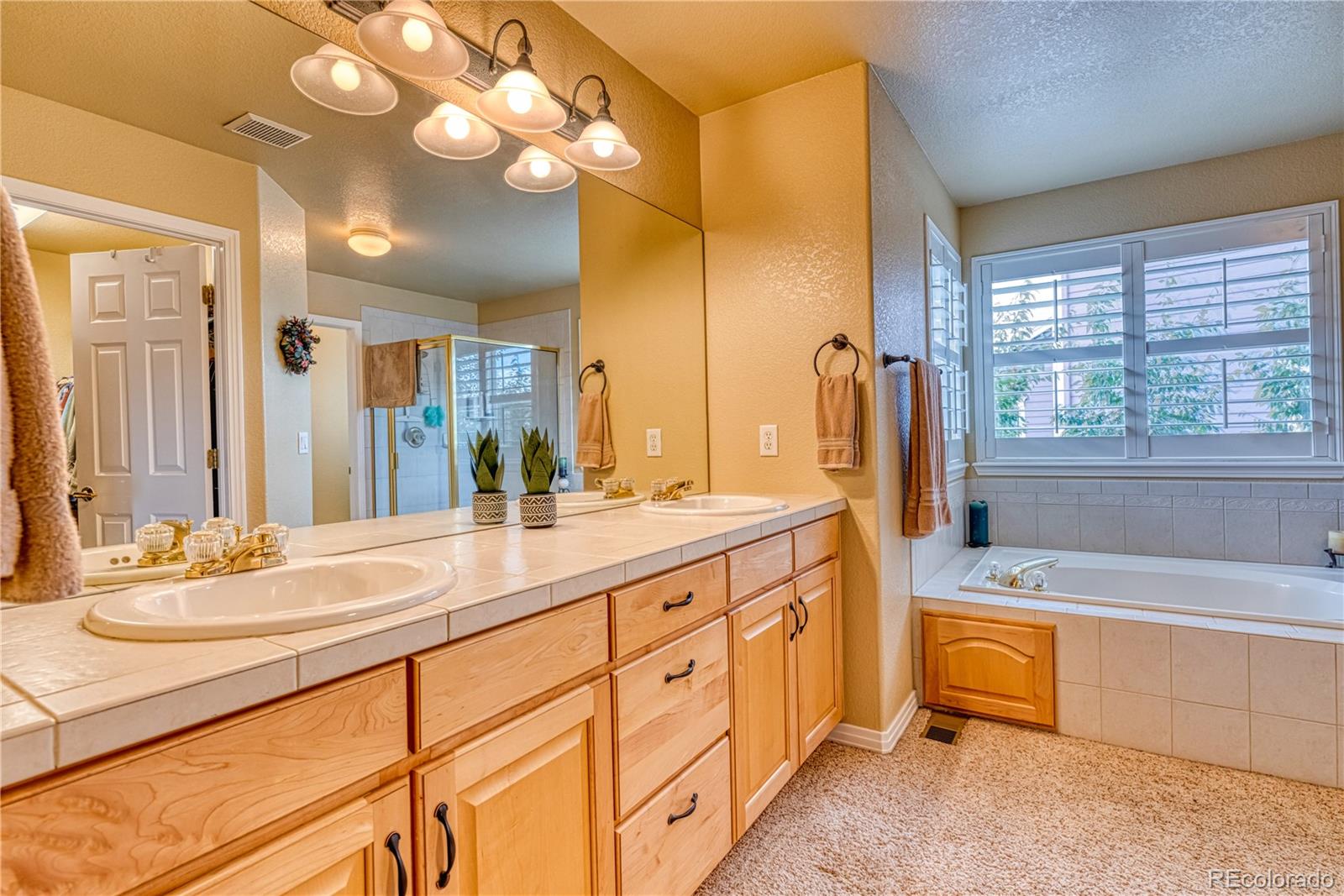 6378 Umber Circle Arvada, CO 80403 - Photo 47 of 50 a spacious bathroom with a double vanity sink a mirror a bathtub and next to a window