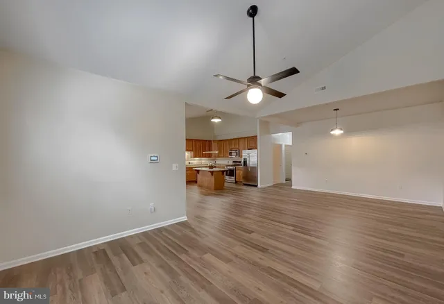 a view of kitchen with stainless steel appliances wooden floor and living room view