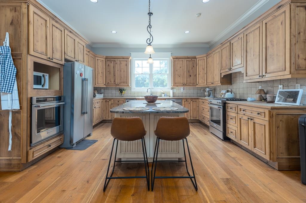 1915 Teague Store Road Somerville, TN 38068 - Photo 17 of 38 Expansive kitchen featuring wood-finish flooring, abundant natural wood cabinetry, stainless steel appliances, a built-in oven, and a central island with a stone countertop