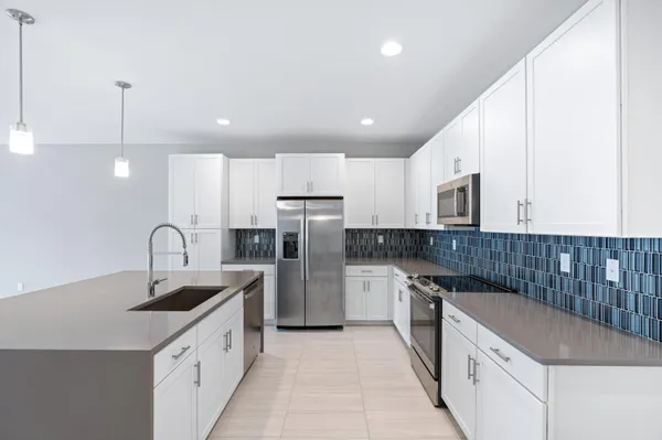 a kitchen with kitchen island granite countertop a sink and refrigerator