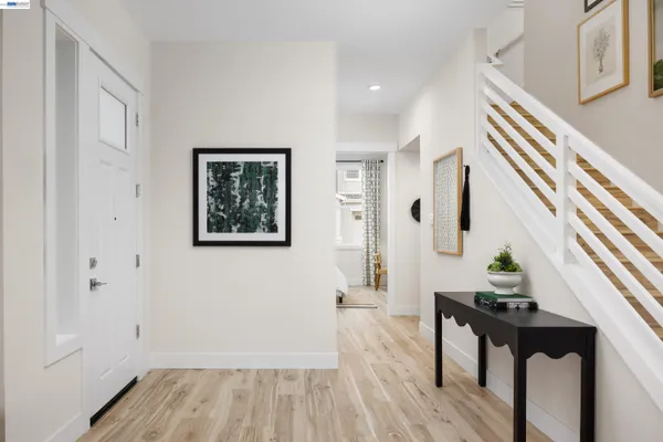 a hallway with wooden floor white walls and stairs