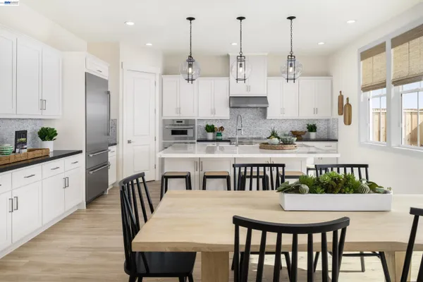 a kitchen with stainless steel appliances kitchen island granite countertop a stove a sink a dining table and chairs