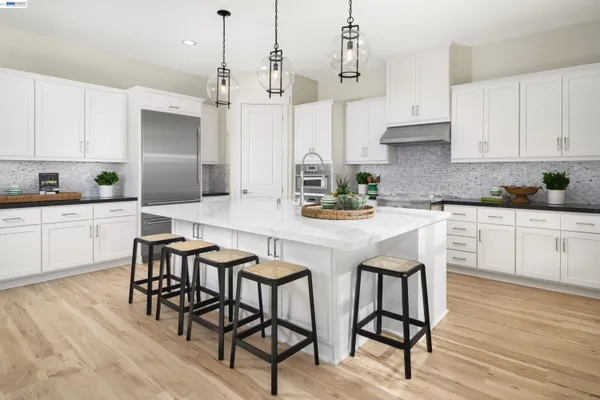 a kitchen with stainless steel appliances kitchen island granite countertop a table chairs sink and cabinets
