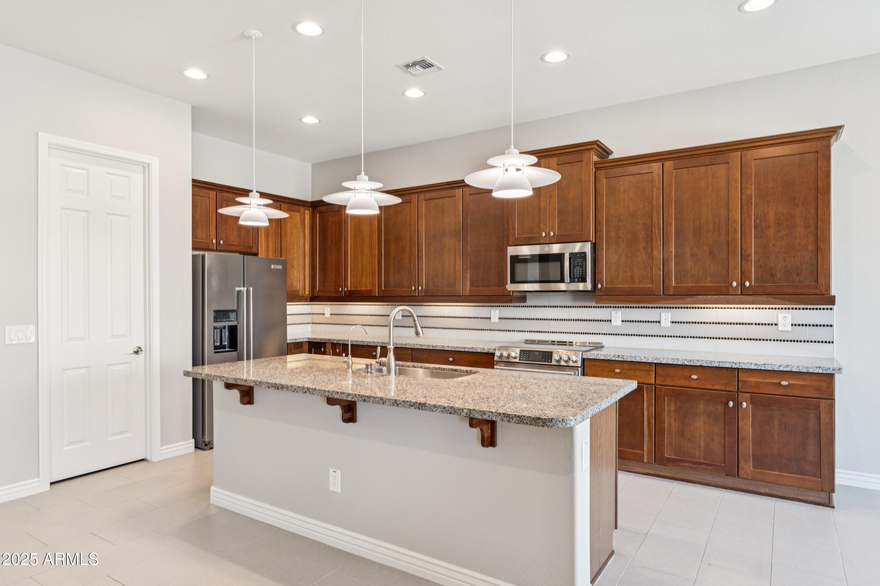 9916 West Redbird Road Peoria, AZ 85383 - Photo 12 of 96 a kitchen with stainless steel appliances a sink stove and refrigerator