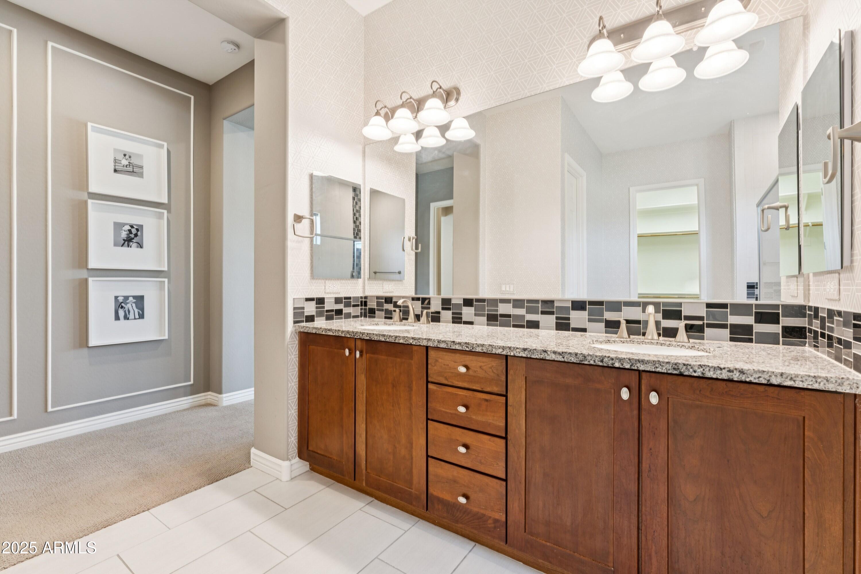 9916 West Redbird Road Peoria, AZ 85383 - Photo 21 of 96 a bathroom with a granite countertop sink a large mirror and a shower