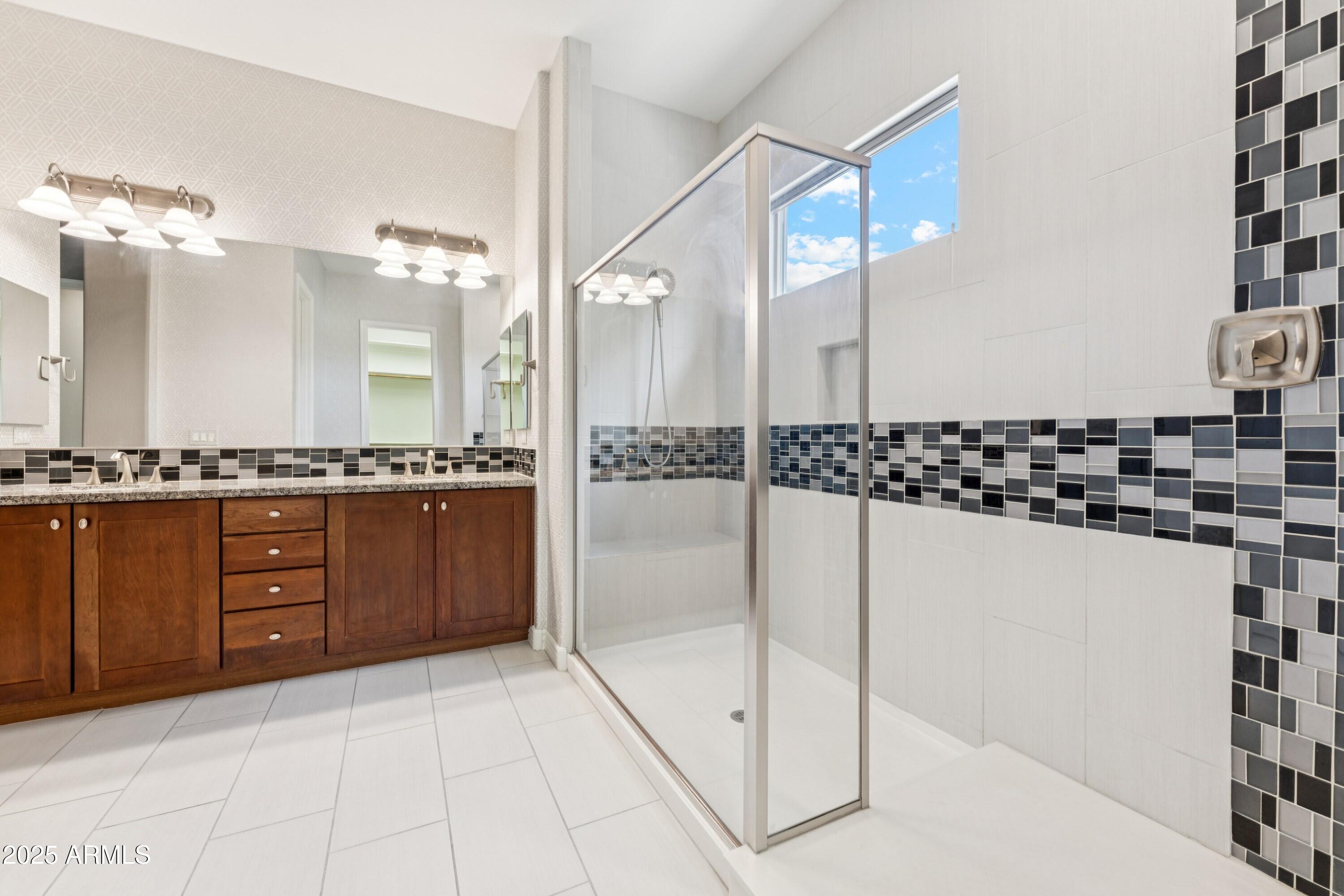 9916 West Redbird Road Peoria, AZ 85383 - Photo 24 of 96 a bathroom with a granite countertop sink a mirror and shower