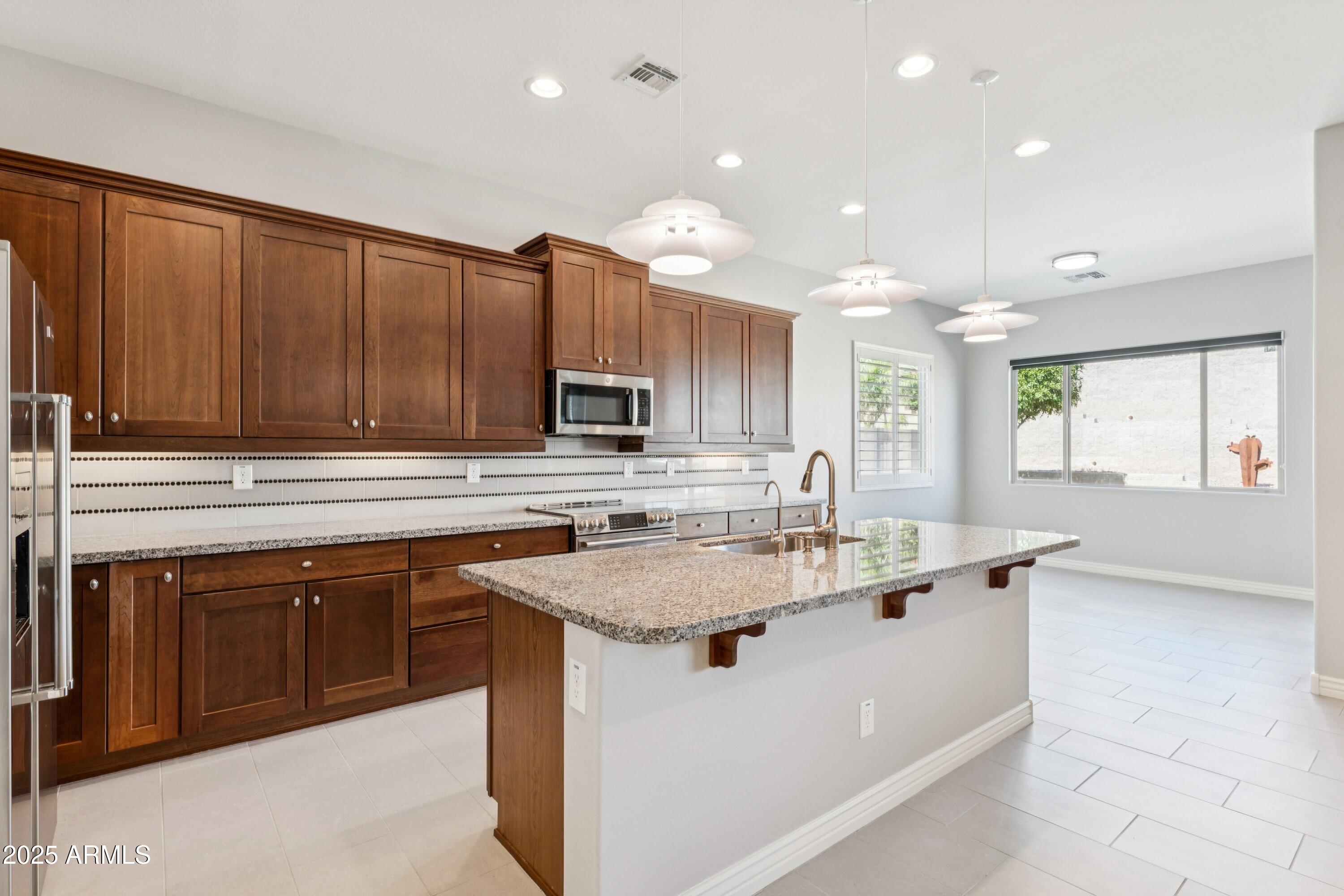 9916 West Redbird Road Peoria, AZ 85383 - Photo 6 of 96 a kitchen with kitchen island granite countertop a sink stainless steel appliances and cabinets