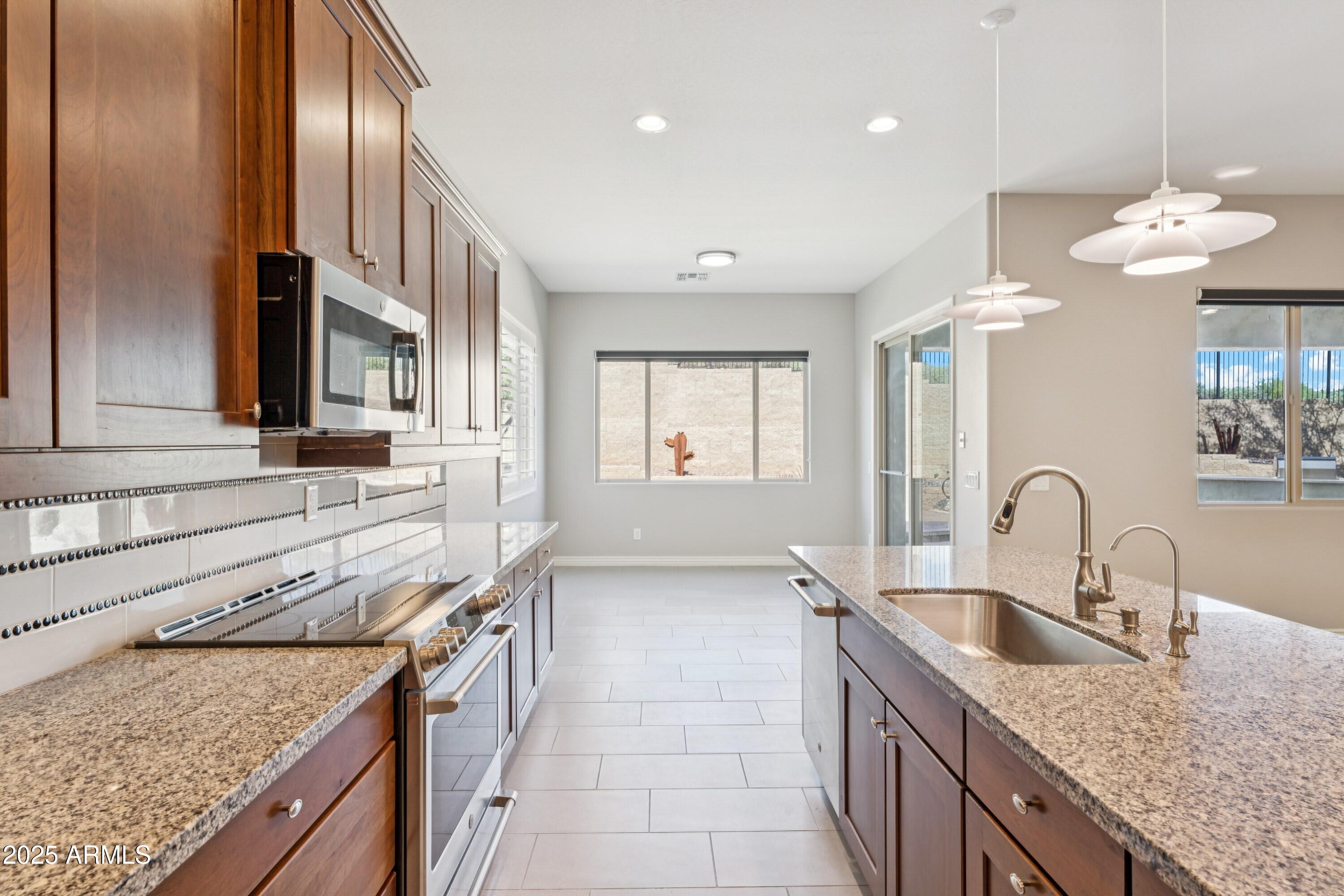 9916 West Redbird Road Peoria, AZ 85383 - Photo 7 of 96 a kitchen with granite countertop stainless steel appliances granite countertop a sink a stove and a wooden floors