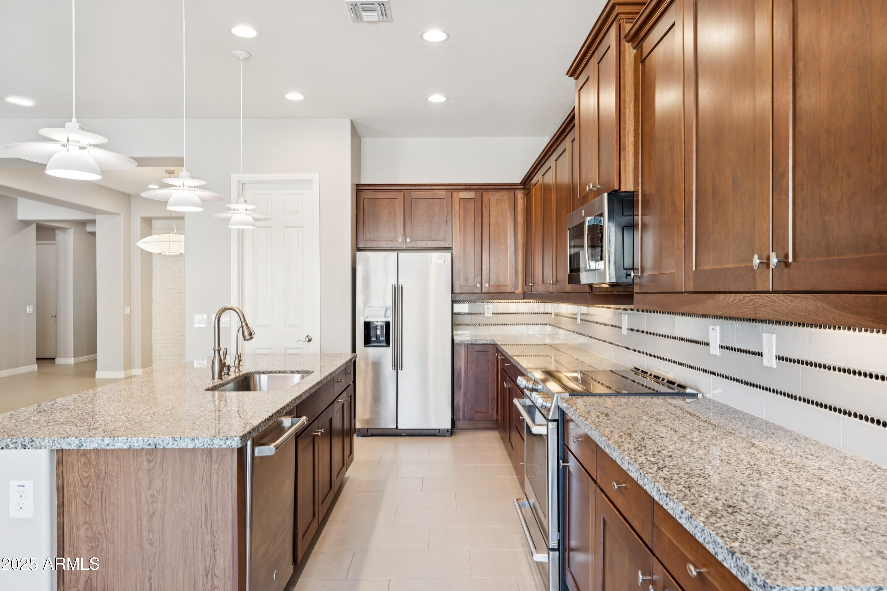 9916 West Redbird Road Peoria, AZ 85383 - Photo 10 of 96 a kitchen with stainless steel appliances granite countertop a sink a stove and a refrigerator