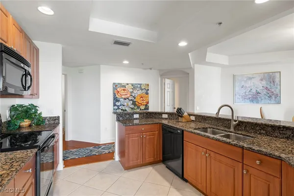 a kitchen with stainless steel appliances granite countertop a stove top oven a sink dishwasher a refrigerator and a microwave