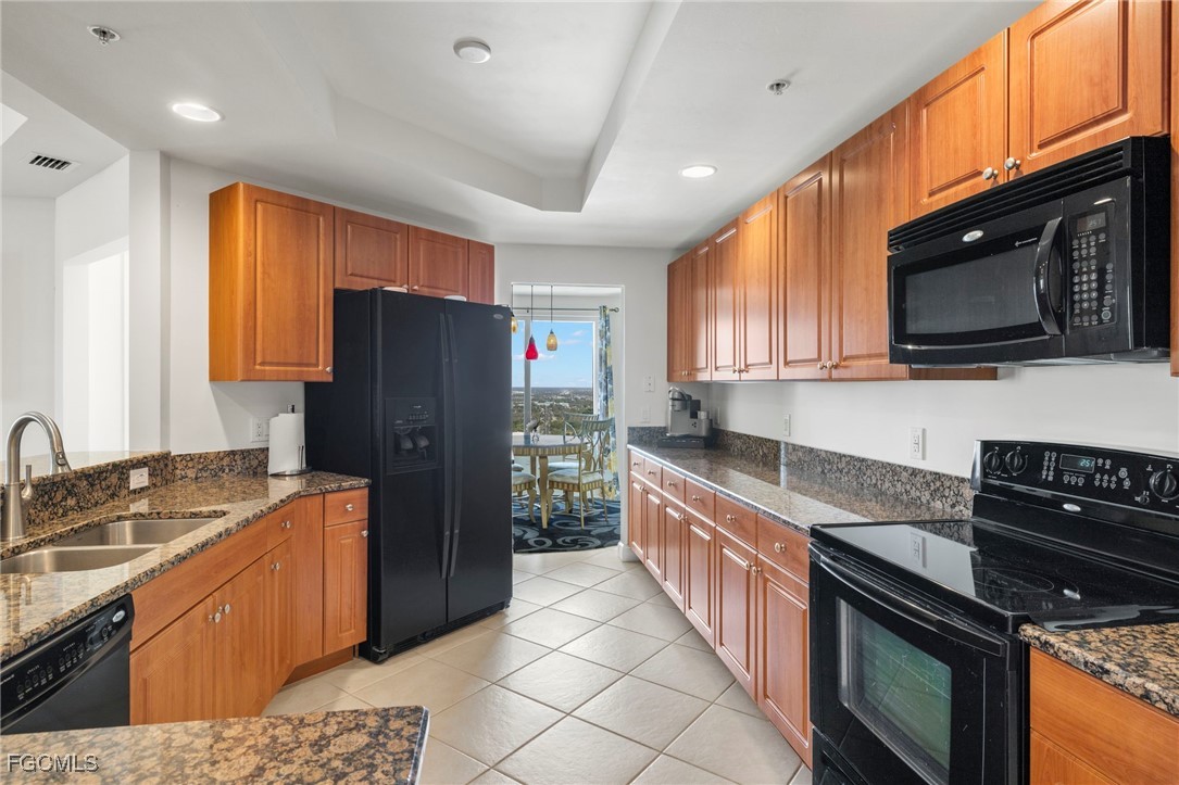 2745 First Street, Unit 2306 Fort Myers, FL 33916 - Photo 7 of 31 a kitchen with stainless steel appliances granite countertop a stove top oven a sink dishwasher a refrigerator and a microwave