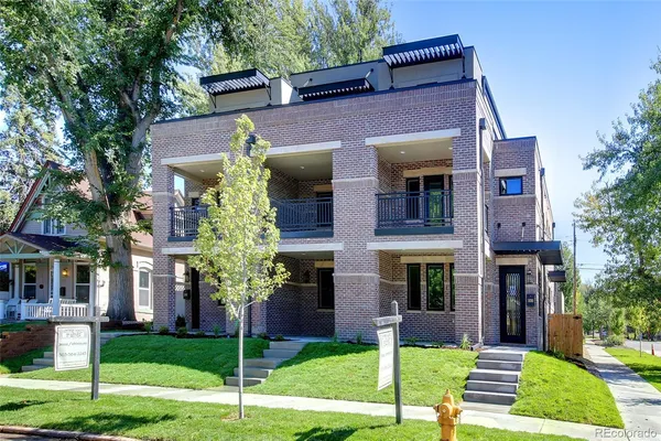a front view of a brick building next to a yard