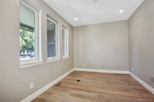 an empty room with wooden floor and windows
