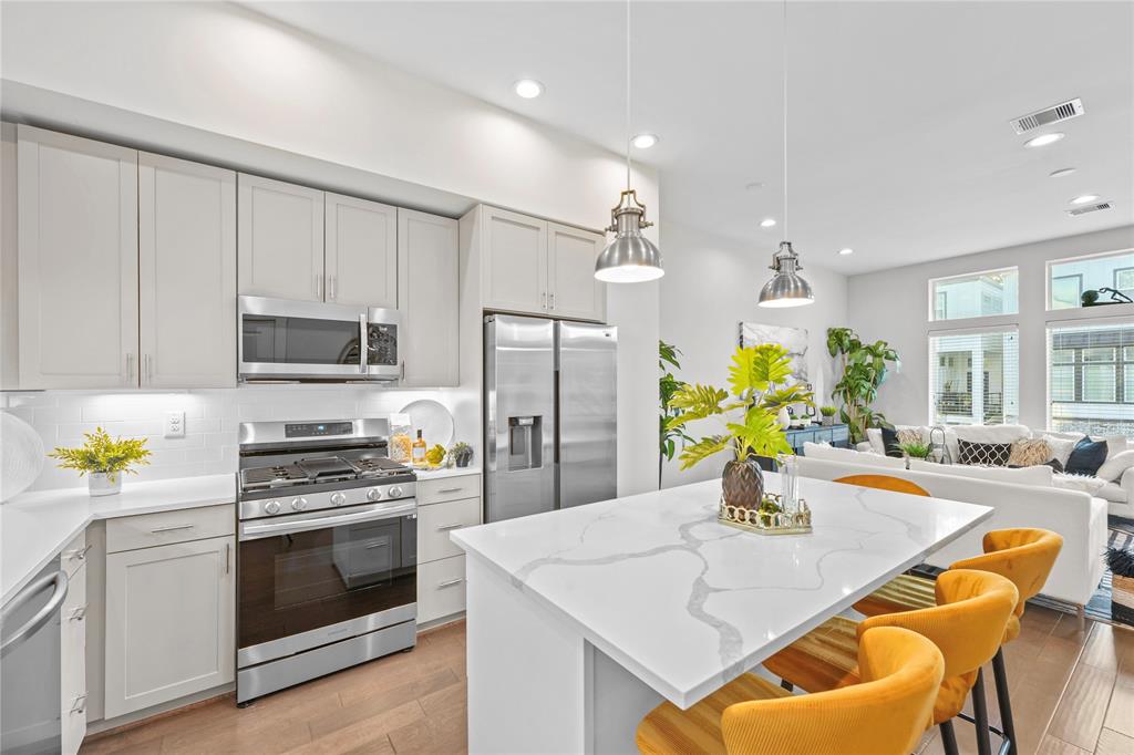 a kitchen with stainless steel appliances kitchen island granite countertop a white cabinets a stove and a center island