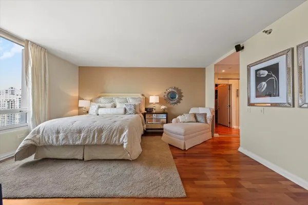 a spacious bedroom with a bed a couch and a potted plant on the dresser