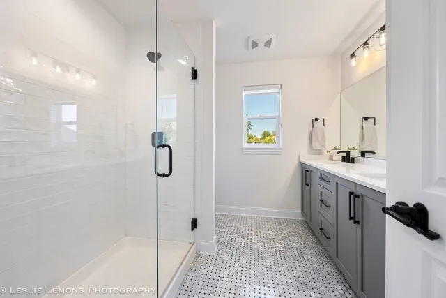 a bathroom with a double vanity sink a toilet a shower and a mirror