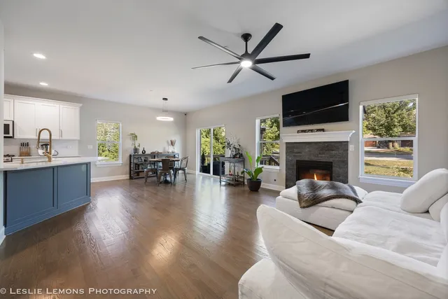 a living room with furniture a fireplace a flat screen tv and a large window