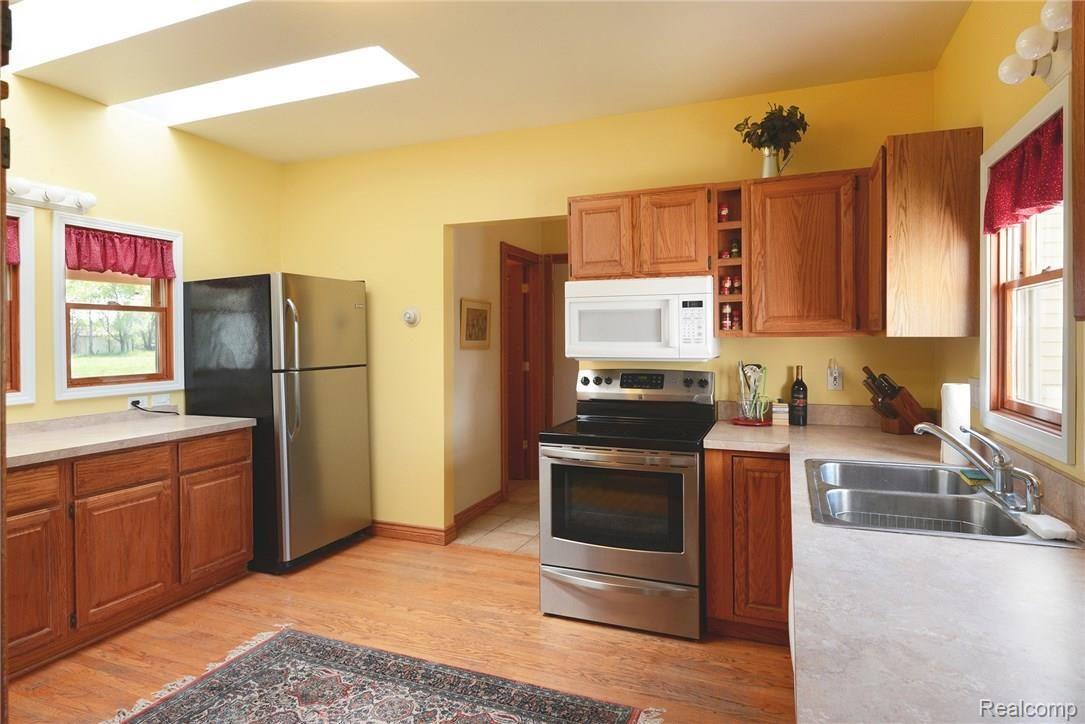4355 North Eager Road Howell, MI 48855 - Photo 8 of 32 Kitchen with stainless steel refrigerator & stove, skylights, and hardwood flooring