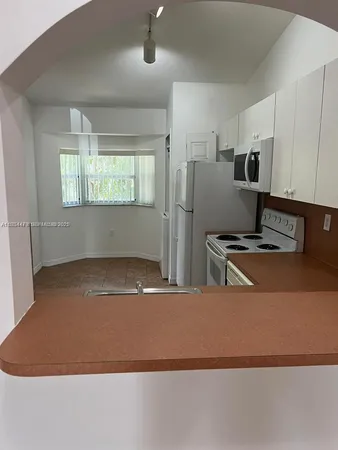 a kitchen with stainless steel appliances granite countertop a refrigerator a stove a sink dishwasher and white cabinets with wooden floor