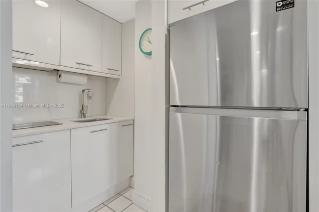 a kitchen with a refrigerator and white cabinets