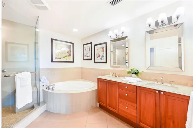 a bathroom with a double vanity sink a toilet a mirror and bathtub